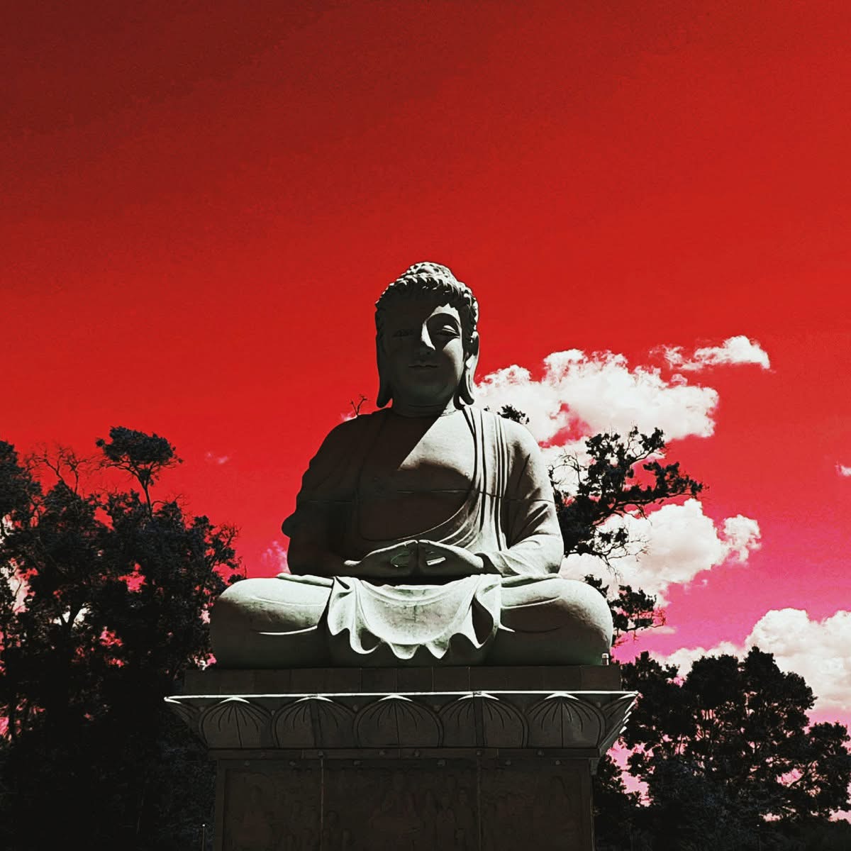 Buddha statue against a crimson sky